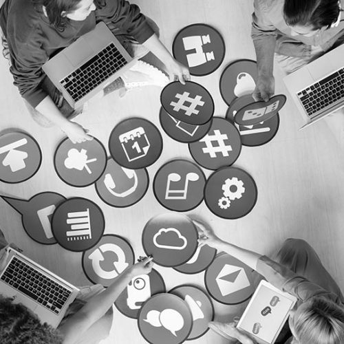 Above view of young social media marketers sitting on floor and using computers while analyzing marketing tools