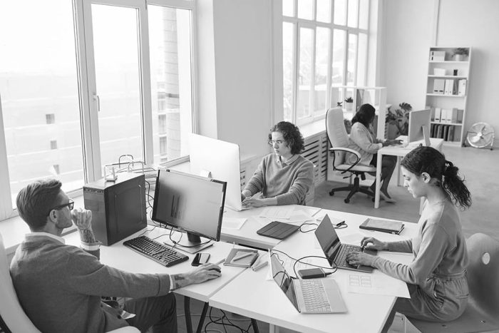 High angle view at diverse software development team using computers at workplace in white office interior, copy space